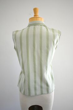 "Description: 1950s/60s green and white striped blouse. Cotton. Ruffled front button placket. Sleeveless. Condition: In great condition, with no holes or stains. Designer: Ship 'n Shore Stated size: 30 Measurements: Armpit to armpit: 18\" Overall length: 20\" Waist: up to 31\" Armhole circumference: 12\" ---> If you need an order shipped by a particular date or shipped via a quicker method, please ask PRIOR to purchase to see if we can accommodate that request. Visit the rest of our shop for Green Top With Striped Collar For Work, Green Tops With Striped Collar For Work, Vintage Striped Summer Blouse, Vintage Collared Top With Vertical Stripes, Vintage Collared Tops With Vertical Stripes, Vintage Striped Tops With Buttons, Retro Green Top For Daywear, Blouse Cotton, Striped Blouse