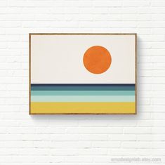 an orange sun on a white brick wall in front of a painting hanging on the wall