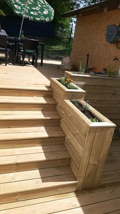 a wooden deck with planters on it and an umbrella in the backgroud