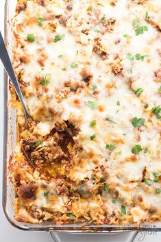 a casserole dish with meat, cheese and parsley in it on a white surface