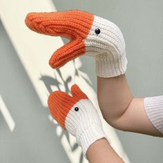 two hands wearing knit mittens with an orange and white bird on them