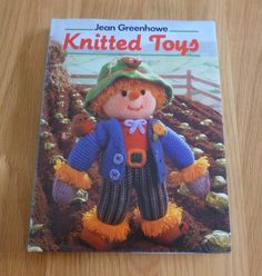 a knitted toy is sitting on a wooden table next to a book titled knitted toys