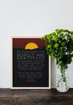 a vase filled with flowers sitting next to a sign on top of a wooden table