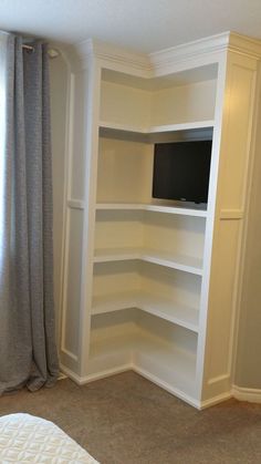 an empty bedroom with white shelving in the corner