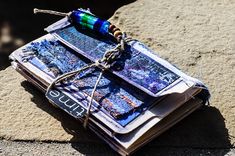 an open book sitting on top of a cement slab next to a tag and string