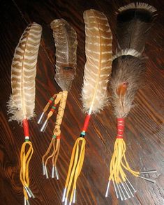 four feathers are lined up next to each other on a table with scissors and thread