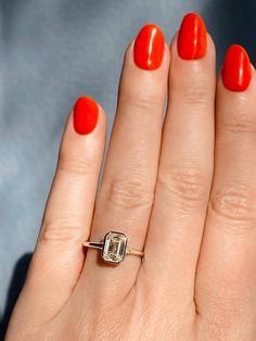 a woman's hand with an orange manicured nail polish and a diamond ring