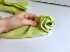 a hand holding a green towel on top of a white counter next to a sewing machine