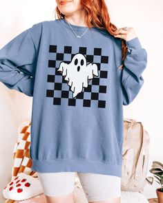 Checkered Ghost Sweatshirt. These sweatshirts are Comfort Colors. The comfort and style are what this unisex, garment-dyed sweatshirt is all about. It's made with 80% ring-spun cotton and 20% polyester and the fabric is 3-end garment-dyed, ring-spun, color-blast fleece with a 100% cotton face. Each sweatshirt comes with a relaxed fit, a rolled-forward shoulder, and a back neck patch.  ✦ 80% Ring-Spun Cotton, 20% Polyester ✦ Color: Pepper, White, Chambray, Butter, Light Green, Blue Spruce, Blue jean, Orchid ✦ Relaxed fit ✦ Medium-heavy fabric ✦ Sewn-in twill label ✦ Eco-friendly, Ethically Made & Sweatshop Free ✦ Printed to order with non-toxic ink ✦ Durable and Long-lasting ✦ Shirts are pre-shrunk but may shrink slightly after washing ✦ Made to order: *Please allow 2-5 business days to pri Halloween Streetwear Crew Tops, Spooky Graphic Print Sweatshirt For Streetwear, Casual Halloween Crew Neck Sweatshirt, Casual Crew Neck Halloween Sweatshirt, Halloween Graphic Print Casual Sweatshirt, Halloween Crew Neck Sweatshirt With Screen Print, Halloween Cotton Sweatshirt With Graphic Print, Halloween Band Merch Sweatshirt With Screen Print, Halloween Graphic Print Cotton Sweatshirt