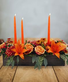 an arrangement of flowers and candles on a table