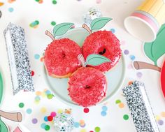 three donuts with pink frosting and sprinkles are on a plate