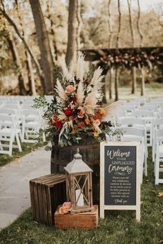 an outdoor ceremony setup with flowers, candles and a welcome sign on the side of the aisle