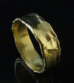 a gold and silver ring sitting on top of a black surface with water droplets in it