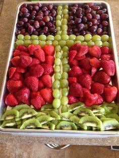 a tray filled with grapes, kiwis and strawberries