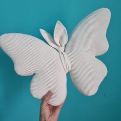 a person holding a white butterfly shaped object in their left hand on a blue background