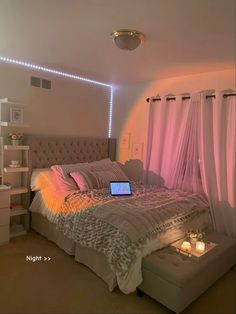 a laptop is sitting on top of a bed in a room with pink drapes