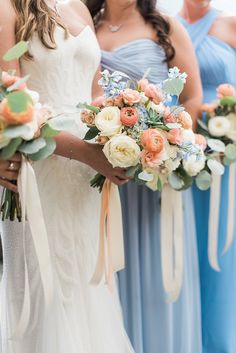 the bridesmaids are holding their bouquets in blue and peach colors, while the groom is wearing a white suit