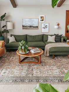 a living room with green couches and pictures on the wall above them, along with a coffee table