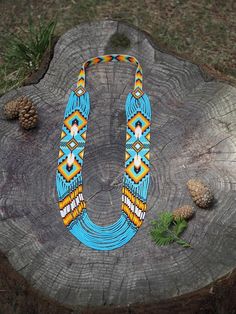 an image of a colorful necklace on a tree stump with pine cones in the background