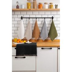 kitchen towels hanging on the wall in front of an oven with fruit and spices behind them