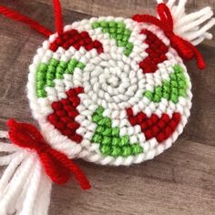 a crocheted ornament with red, green and white trim on a wooden surface