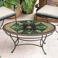 a mosaic table with two chairs and a potted plant in the background on a patio