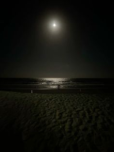 two people are standing on the beach at night