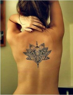 the back of a woman's body with a lotus tattoo on her left side