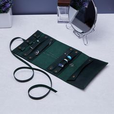 a pair of scissors and a green case on a white table next to a mirror