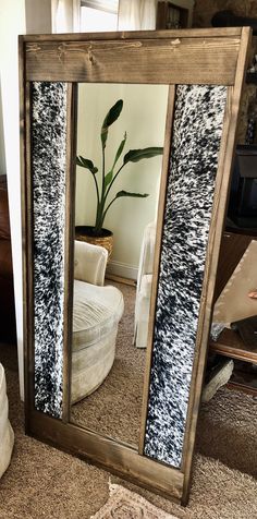 a large mirror sitting on top of a floor next to a white chair and potted plant