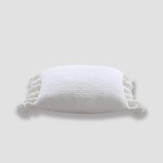 a white pillow with tassels on it