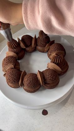 someone is decorating a chocolate cake with icing on a white plate and holding a knife