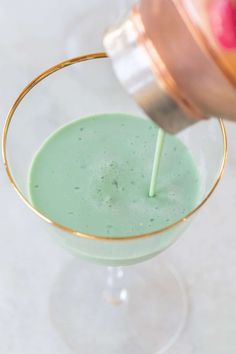 a drink being poured into a glass with an apple in the background and a straw sticking out of it