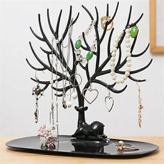 a black tray holding a tree with jewelry on it