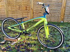 a blue and yellow bike parked in front of a wooden fence