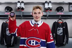 a hockey player is holding up his jersey in front of the wall with other jerseys on it