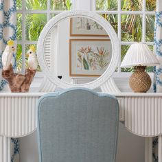 a mirror sitting on top of a table next to a blue chair and two birds