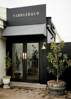 the front entrance to saddler & co with potted plants in pots on the sidewalk