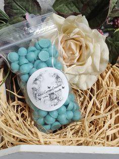 a box filled with blue and white candies next to a flower on top of straw