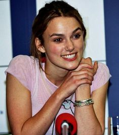 a woman sitting in front of a microphone with her hand on her chin and looking at the camera