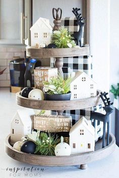 three tiered trays with ornaments and house decorations on them in the middle of a kitchen