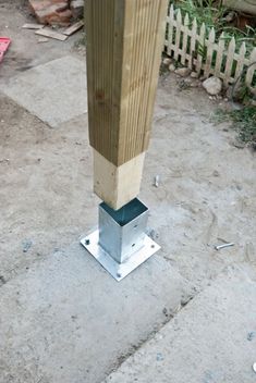 a wooden post with a metal base on the ground