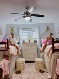 two women sitting on bunk beds in a room with pink and white bed linens