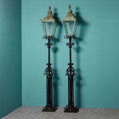 two old fashioned street lamps against a blue wall in a room with tile flooring