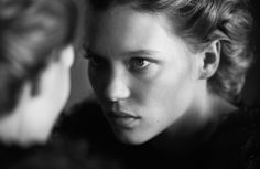 a black and white photo of a woman looking in the mirror