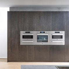 a kitchen with three ovens mounted to the side of a wall next to a counter