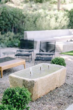 an outdoor living area with chairs, tables and fire pit in the middle of it