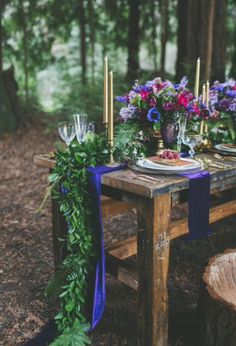 the table is decorated with flowers, candles and napkins for an outdoor wedding reception