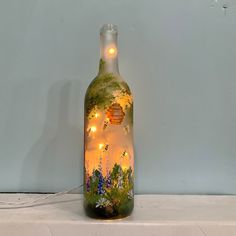 a glass bottle with lights in it sitting on top of a white table next to a wall