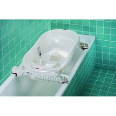 a bath tub with a toilet seat attached to the side and green tiled wall behind it